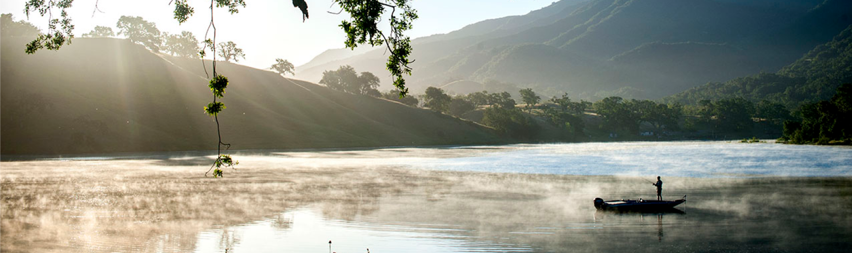 Person standing up in a canoe fishing on a lake