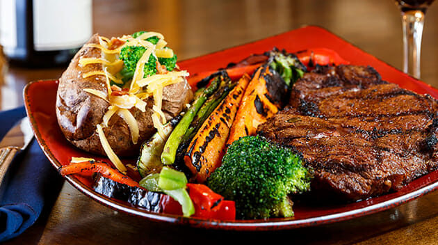 Plate of meat, vegetables, and baked potato