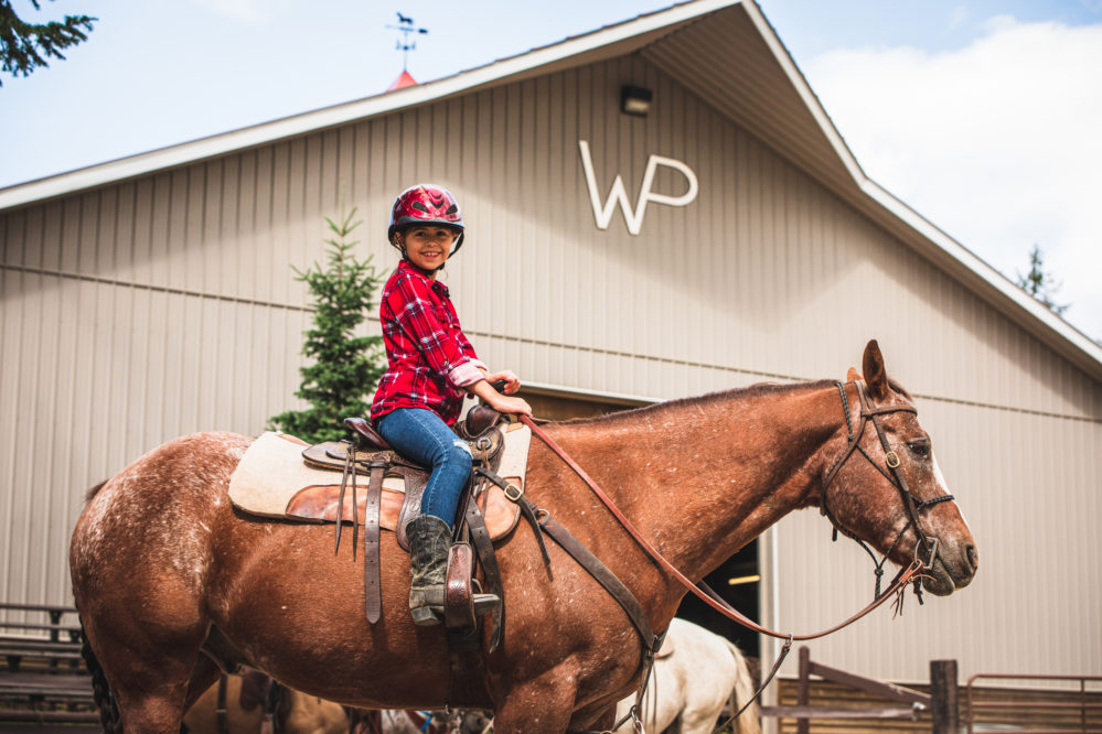Little girl on a horse in front of Barn