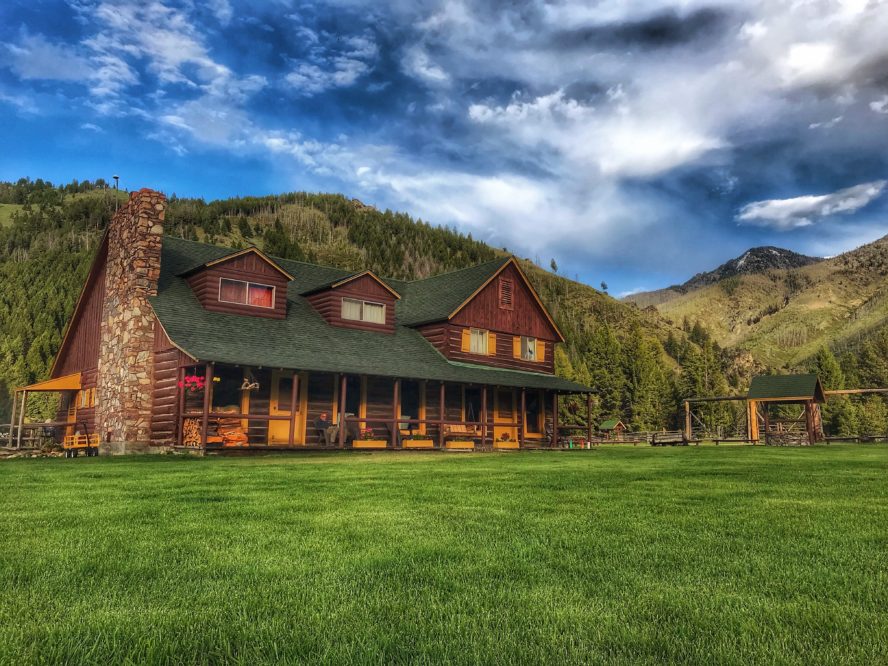 log cabin lodge with green lawn and blue sky with clouds