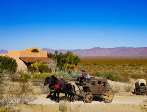 Stagecoach wagon being pulled by two horses with Mountains in background