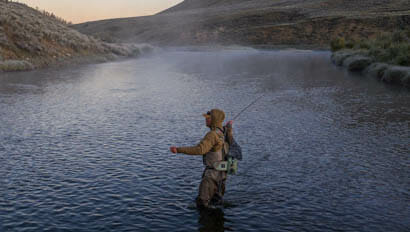 Guest fly fishing in a river with fog at A Bar A Ranch