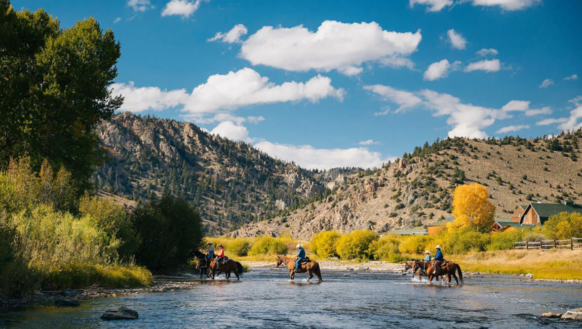Riders crossing a river at A Bar A Ranch