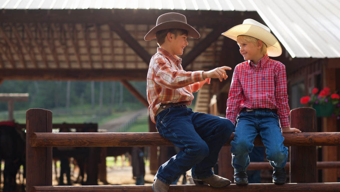 Two kids sitting on a fence at Averills Ranch