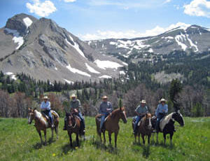 Guests on horses in a line in front of mountains at Elkhorn Ranch Montana