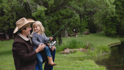 Dad holding young daughter as they fish together at Greenhorn Ranch