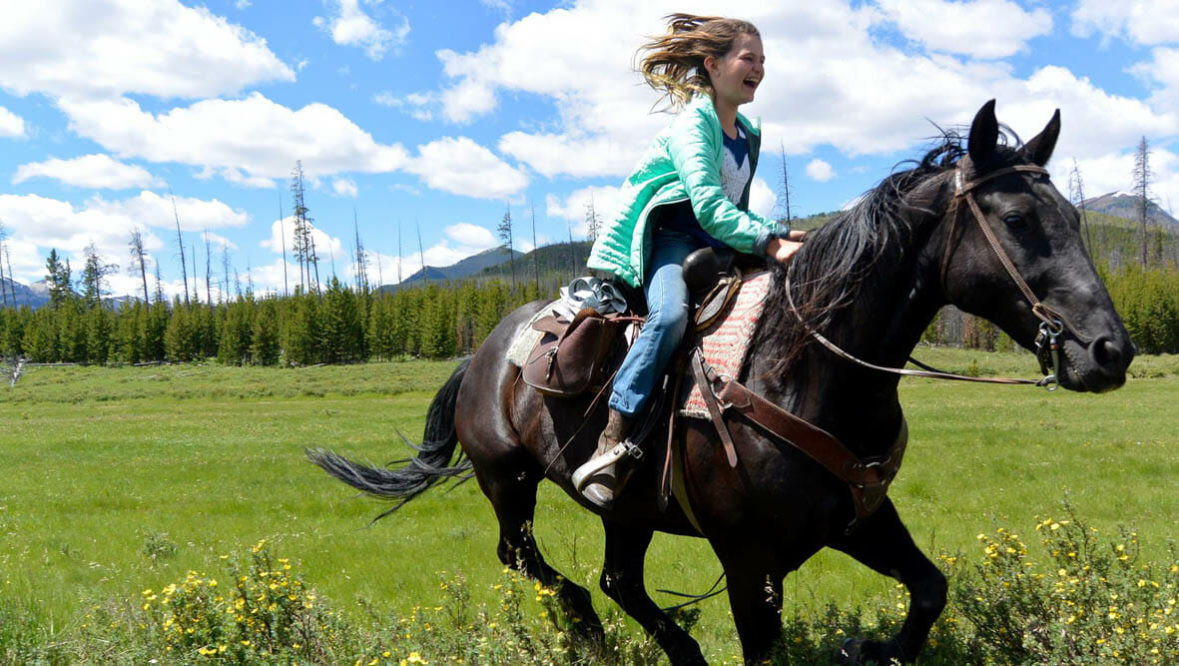 Girl loping on a horse at JJJ Wilderness Ranch