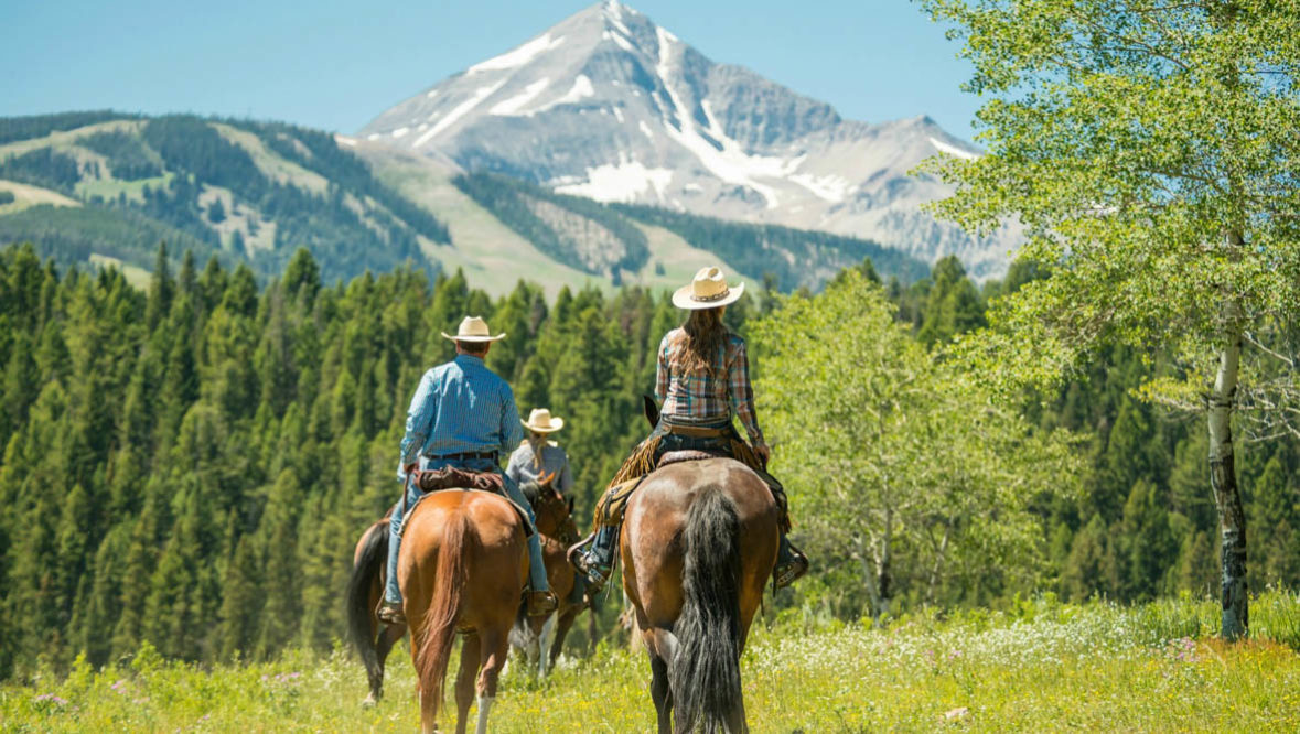 Two guests on horses looking at the mountains at Lone Mountain Ranch