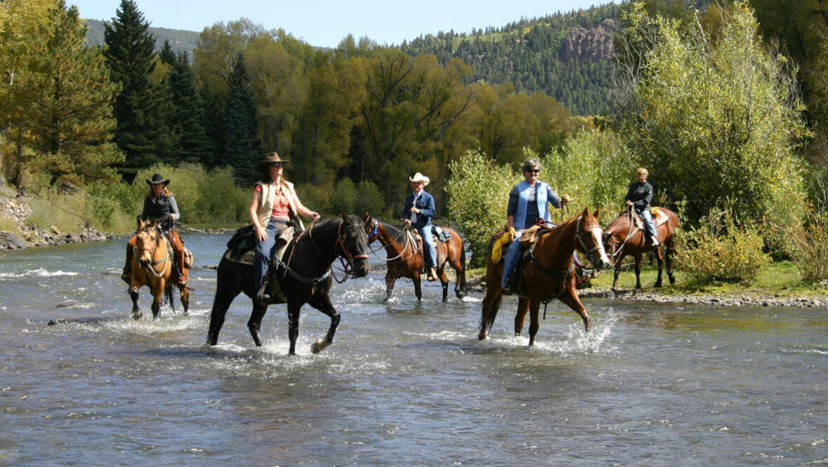 Trail ride through a river at Rainbow Trout Ranch