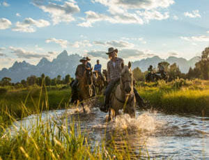 Riders and Horses crossing a river at Triangle X Ranch