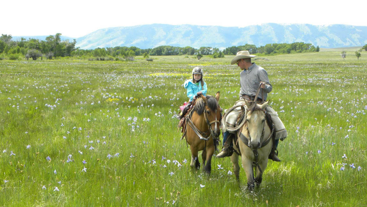 Kid and adult on horses at Vee Bar Ranch