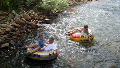 Kids and dad floating down a creek on tubes at Vee Bar Ranch