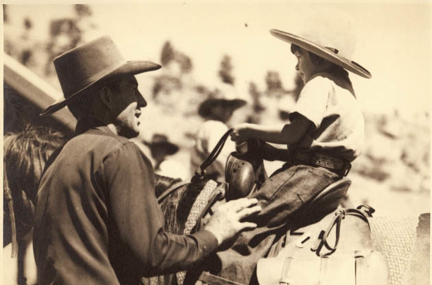 Historical photo of a father with his hand on his young son on a horse