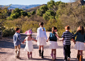 Kids holding hands walking down a trail