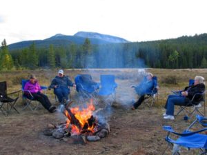People in chairs around a campfire