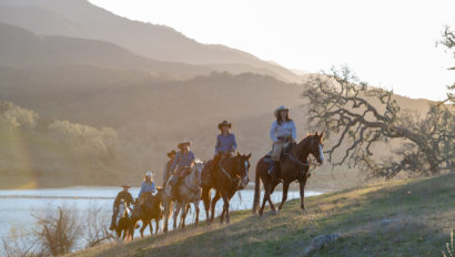 people on horses going up a hill