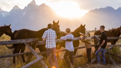 2 kids and an adult petting horses